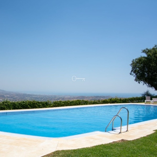 Relaks przy basenie z widokiem na góry i morze, komfortowa przestrzeń wypoczynkowa.