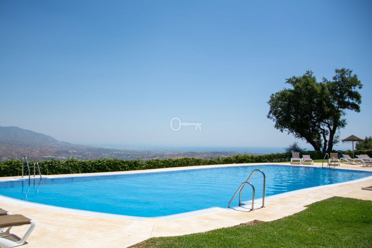 Relaks przy basenie z widokiem na góry i morze, komfortowa przestrzeń wypoczynkowa.