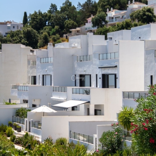 Stylowe białe domy na wzgórzu z bujną roślinnością — idealny krajobraz do inwestycji i nieruchomości w Hiszpanii.