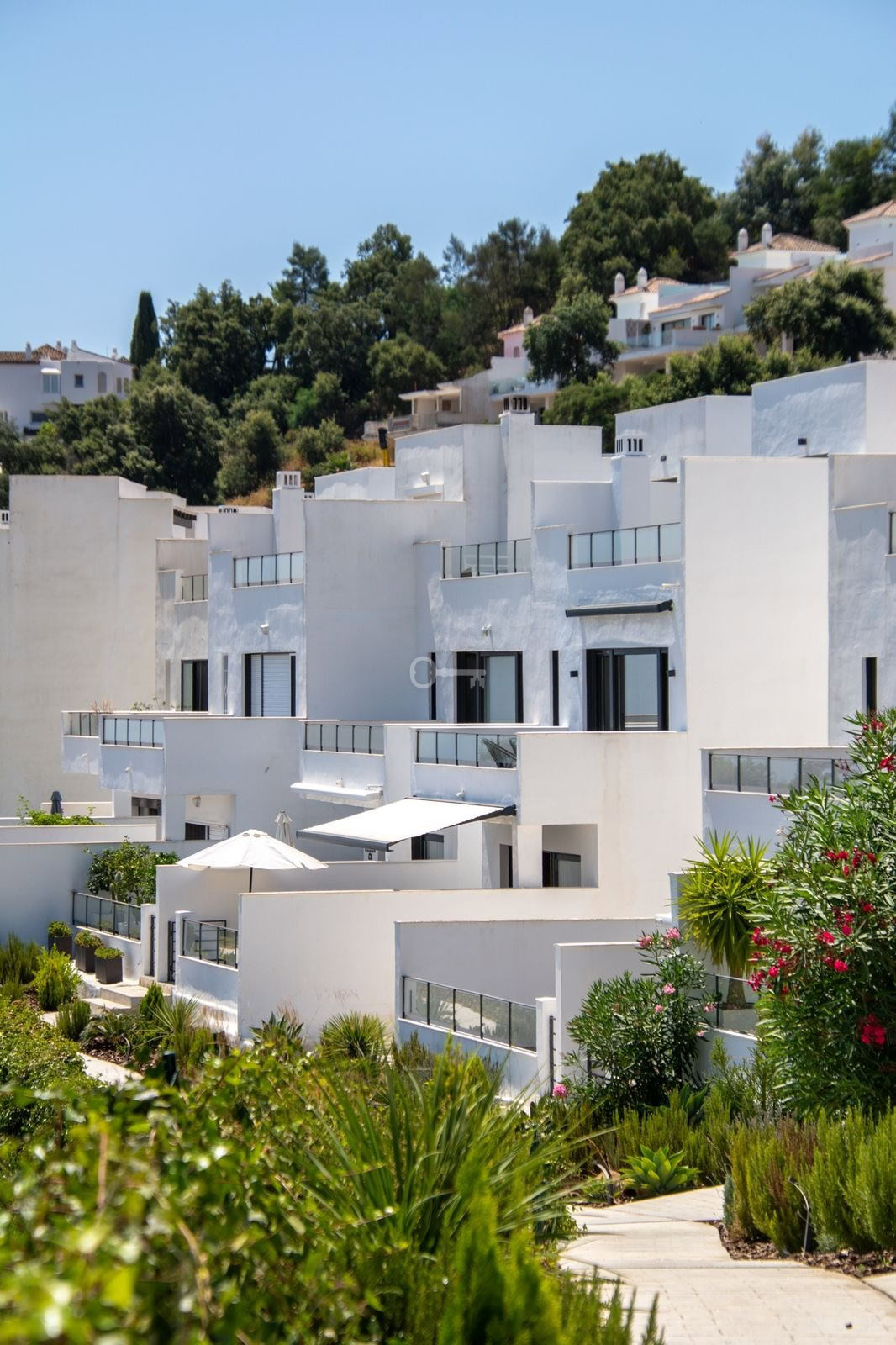 Stylowe białe domy na wzgórzu z bujną roślinnością — idealny krajobraz do inwestycji i nieruchomości w Hiszpanii.