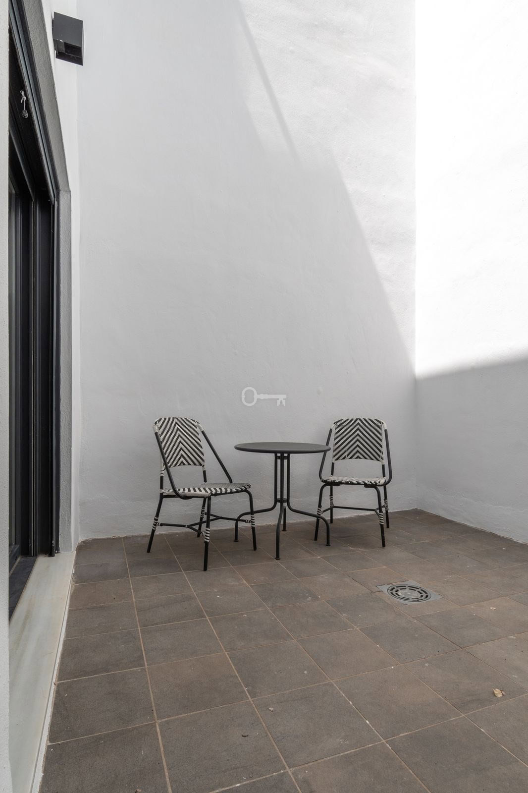 Nowoczesny patio z dwoma krzesłami i małym stolikiem, idealne do relaksu i spotkań.