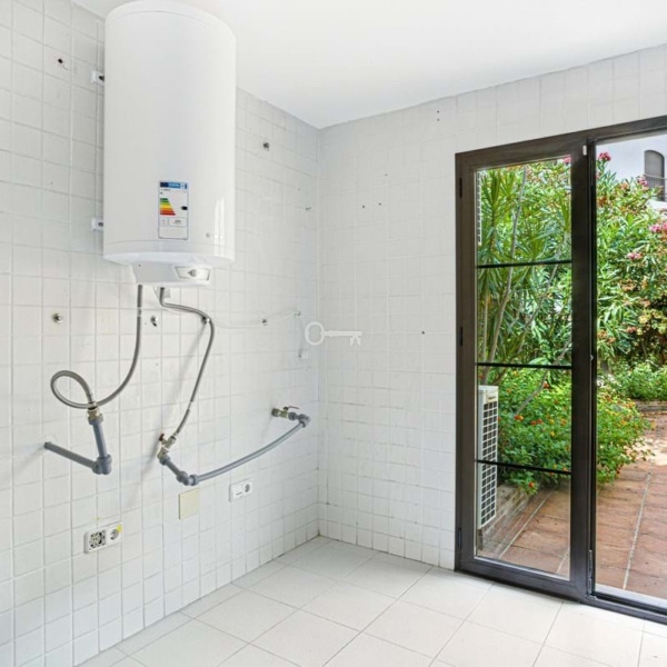 Pralka i podgrzewacz wody w jasnej kuchni z wyjściem na zielony ogród, idealne rozwiązanie dla domu.