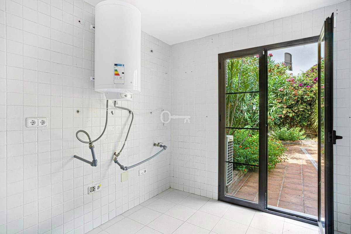 Pralka i podgrzewacz wody w jasnej kuchni z wyjściem na zielony ogród, idealne rozwiązanie dla domu.