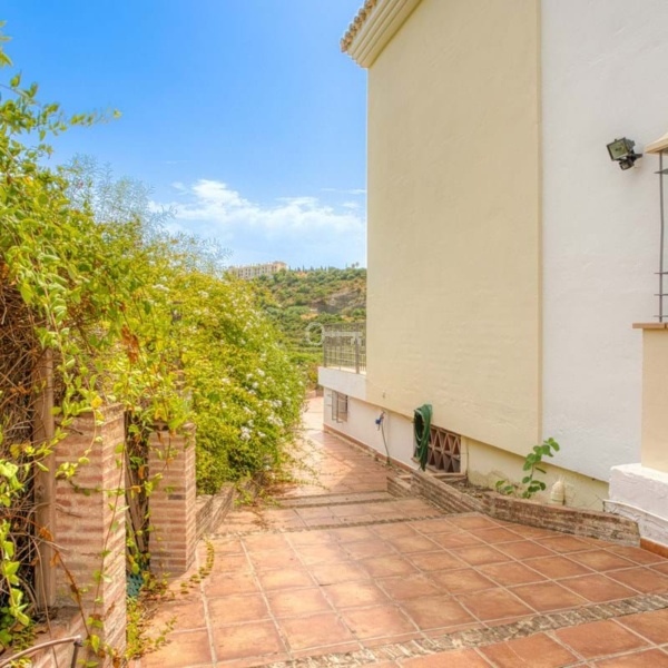 Przestronny taras z widokiem na zielony ogród i krajobraz. Idealne miejsce do relaksu i spotkań na świeżym powietrzu.