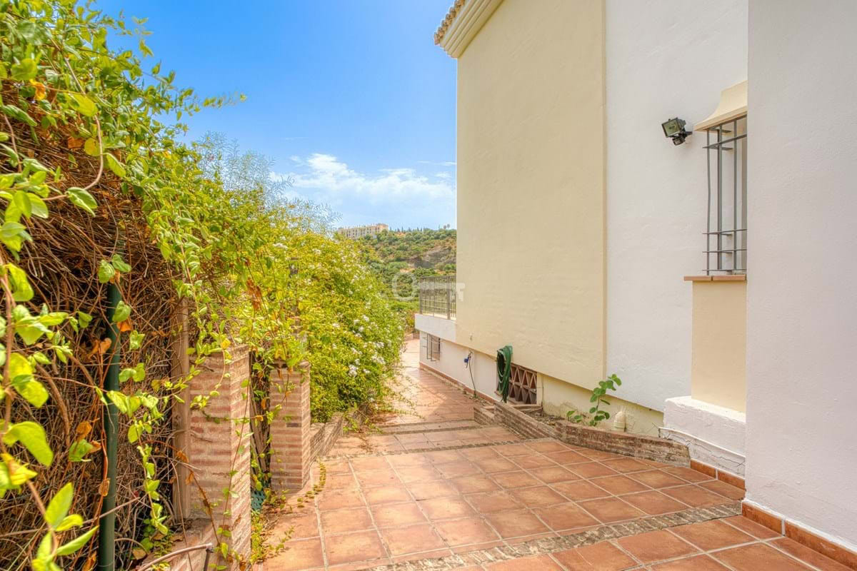 Przestronny taras z widokiem na zielony ogród i krajobraz. Idealne miejsce do relaksu i spotkań na świeżym powietrzu.