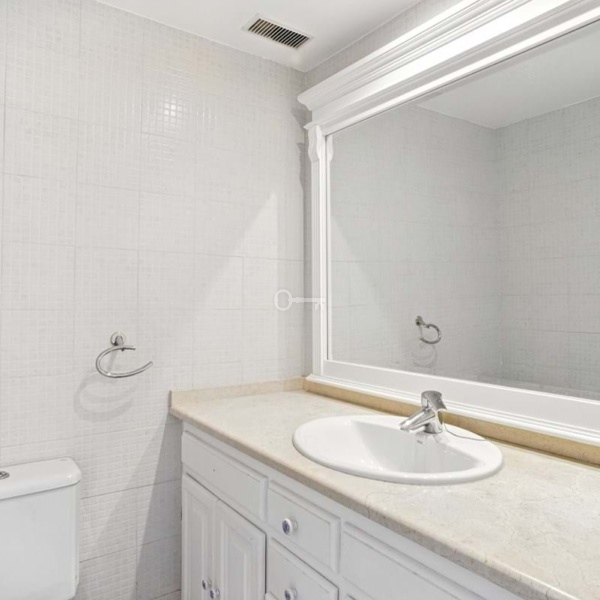 Odbicie w łazience z lustrem i umywalką, nowoczesne wykończenie wnętrza, białe elementy, minimalistyczny styl.