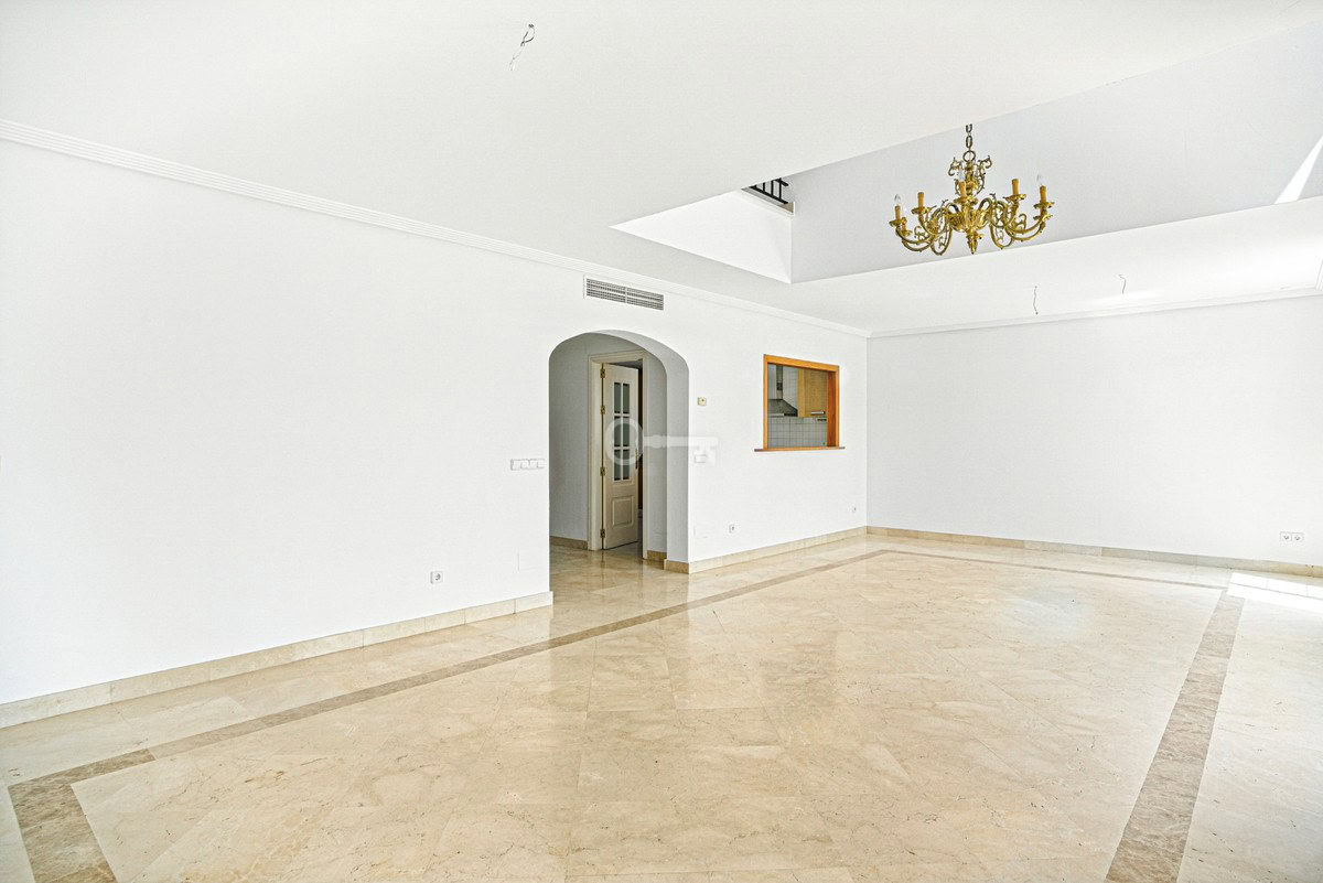 Przestronne wnętrze mieszkania z białymi ścianami i marmurową podłogą.