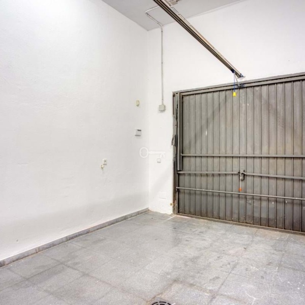 Przestronna garażowa brama w nowoczesnym garażu z białymi ścianami i wykładziną podłogową.