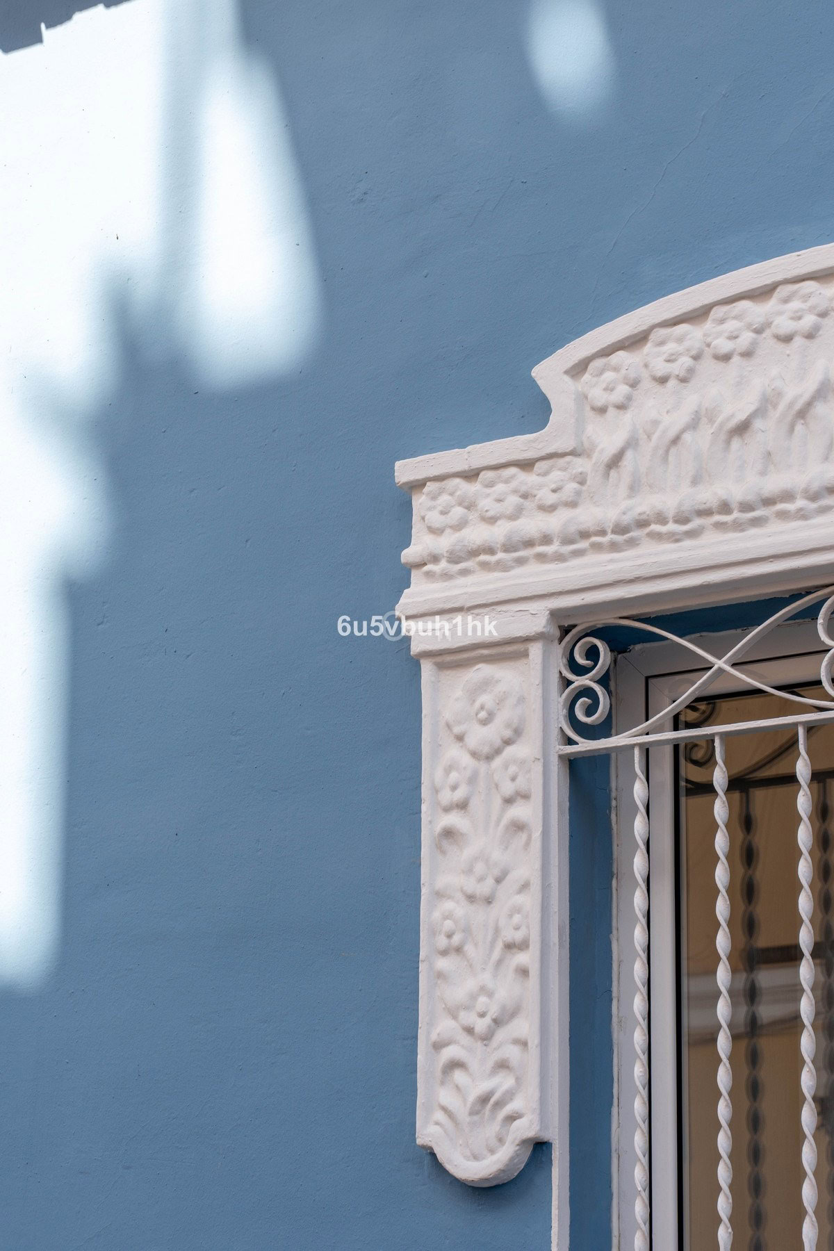 Klimatyczne detale architektoniczne na jasnoniebieskiej ścianie, ozdobiony drewnianym ornamentem.