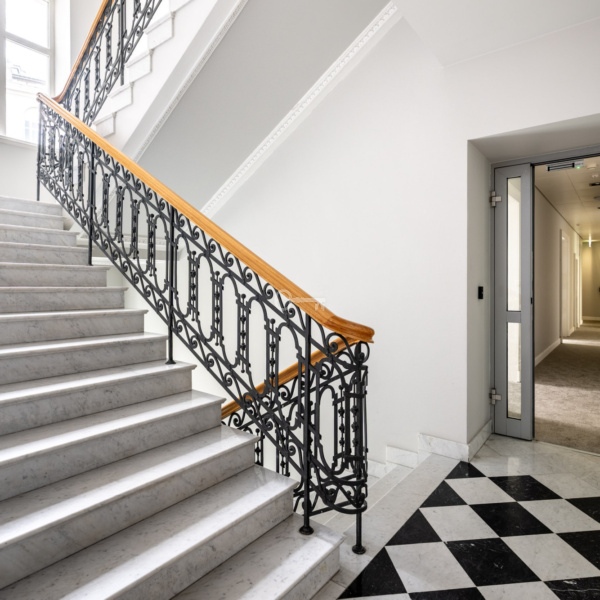 Klasywne schody z marmuru z ozdobnym kutym poręczą, elegancka przestrzeń w budynku.