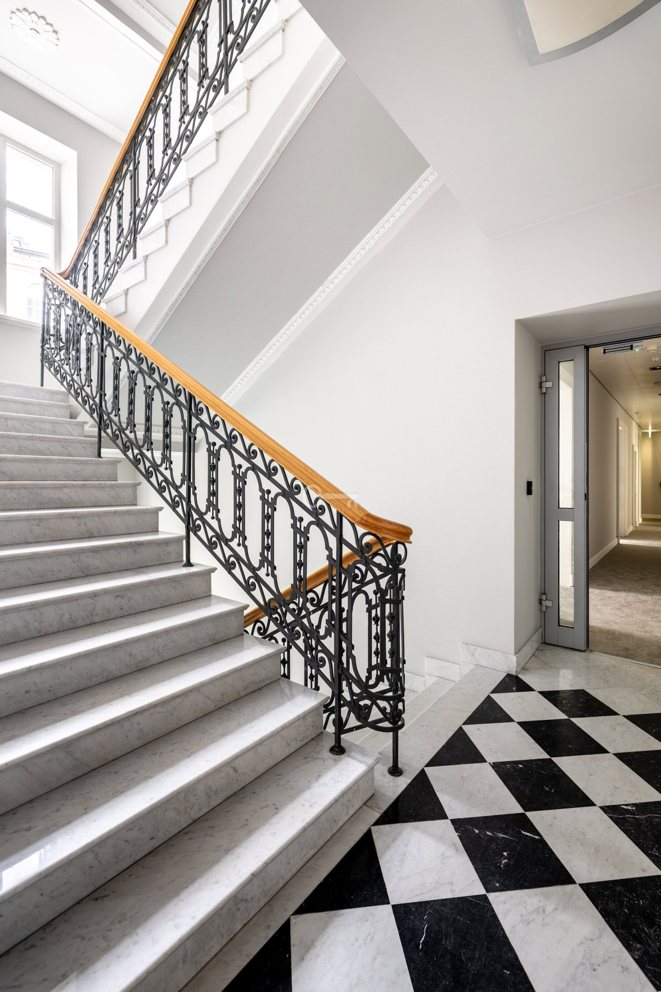 Klasywne schody z marmuru z ozdobnym kutym poręczą, elegancka przestrzeń w budynku.